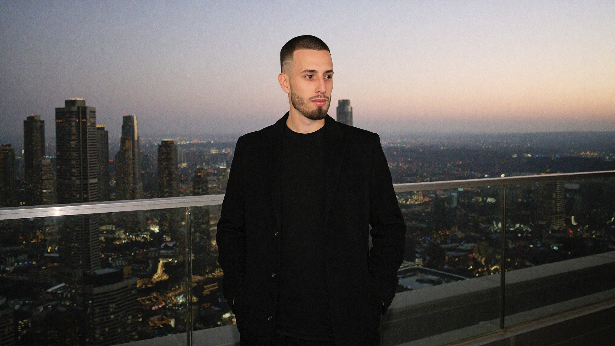 Cody Wise on a rooftop at dusk overlooking a city skyline