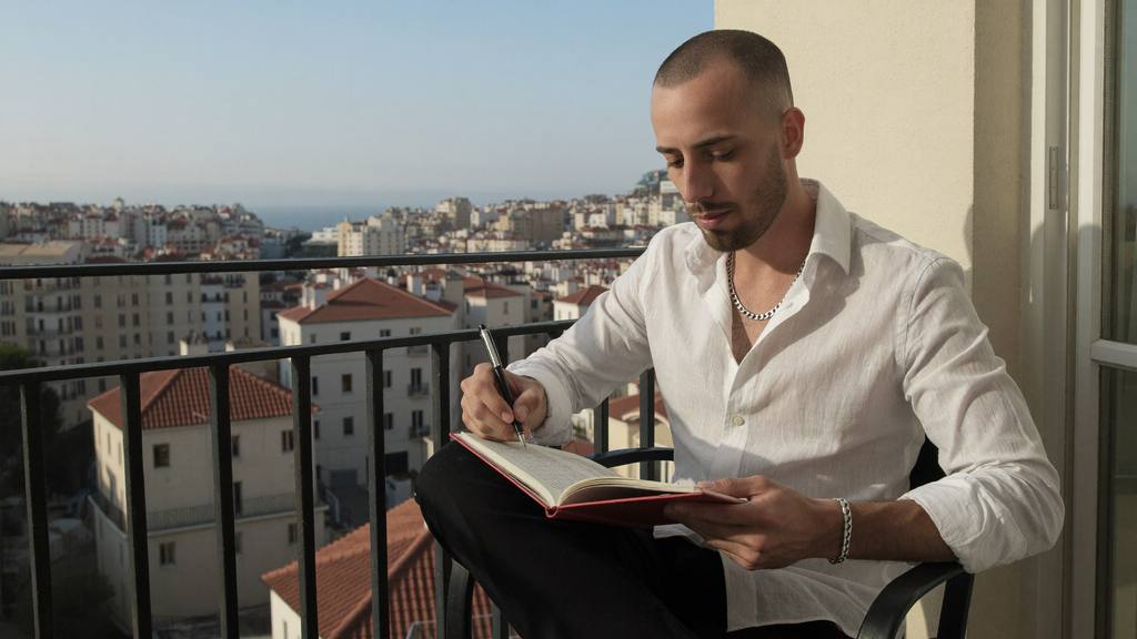 Cody Wise writing in a journal on a Mediterranean balcony in morning light