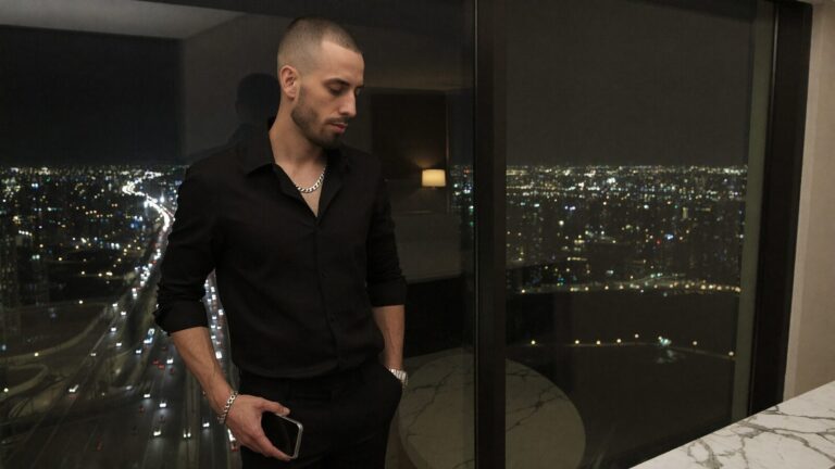 Cody Wise at a Dubai high-rise window at night, the city where QUBI DAO builds its RWA tokenization platform