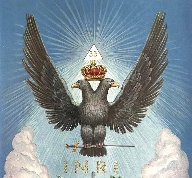 A crowned double headed eagle holding a sword, with the numeral 33 in a triangle above it and the letters INRI in stars below