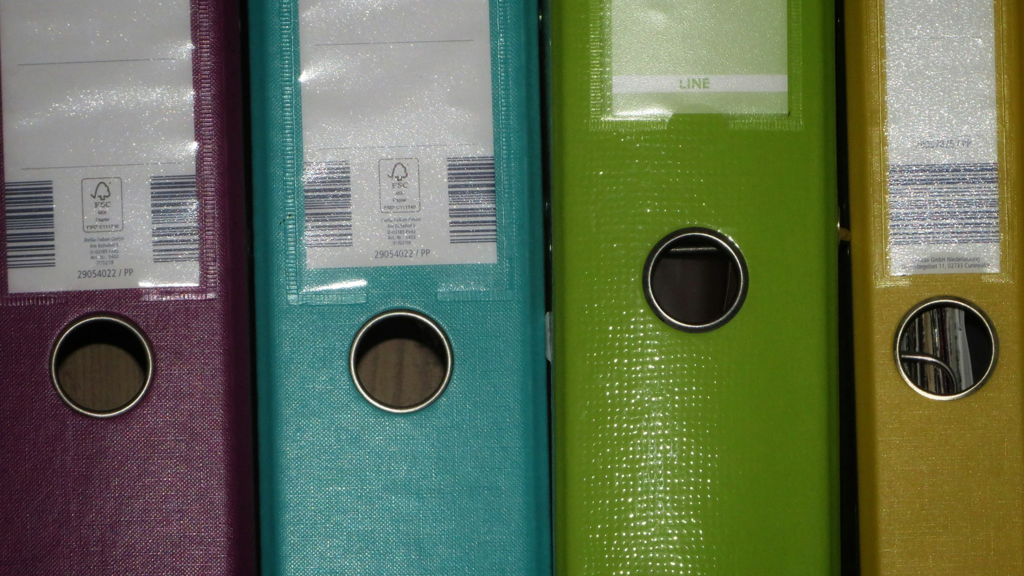 A row of colored binders lined up on a shelf