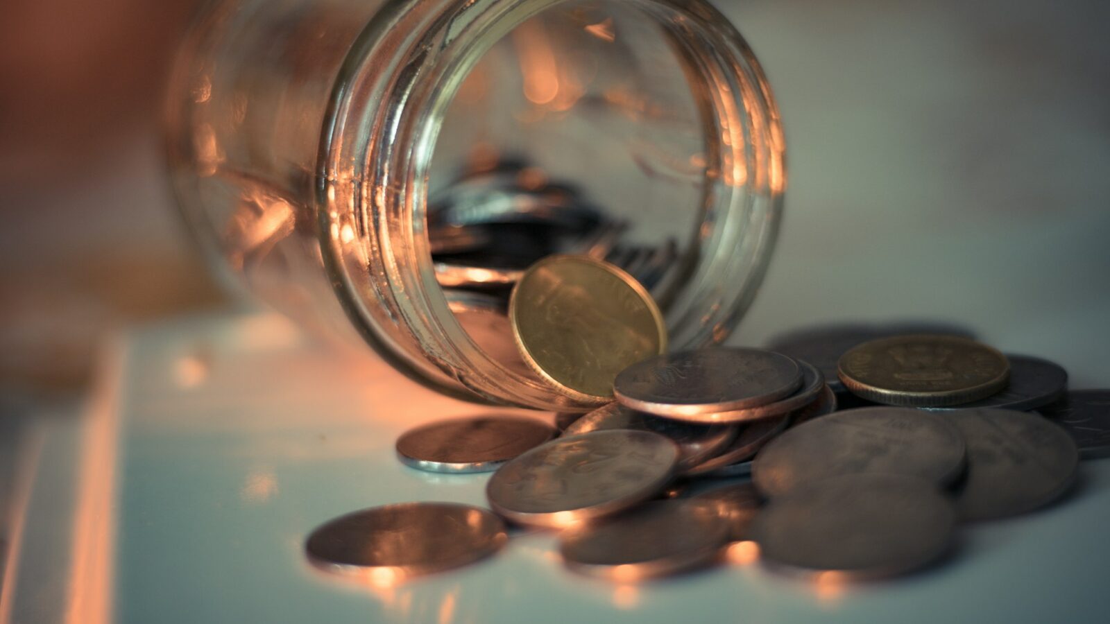 A clear glass jar filled with coins on a table