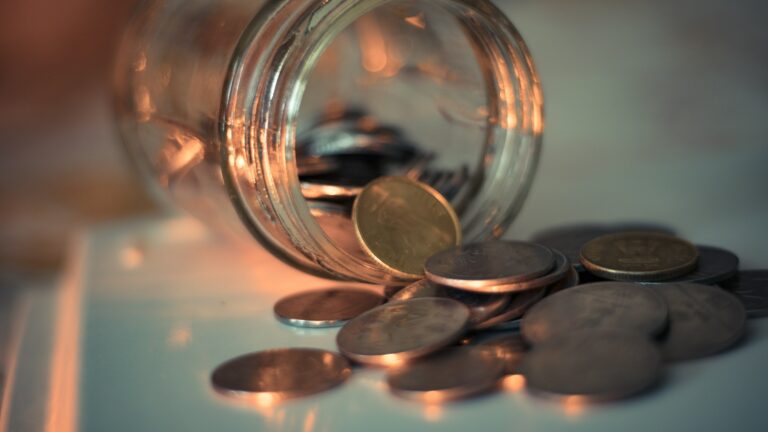A clear glass jar filled with coins on a table