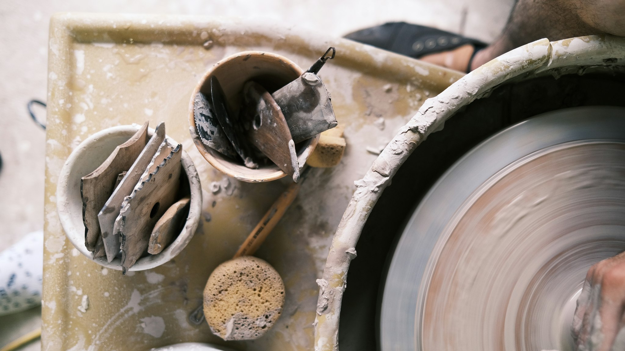 Hands shaping wet clay on a spinning pottery wheel