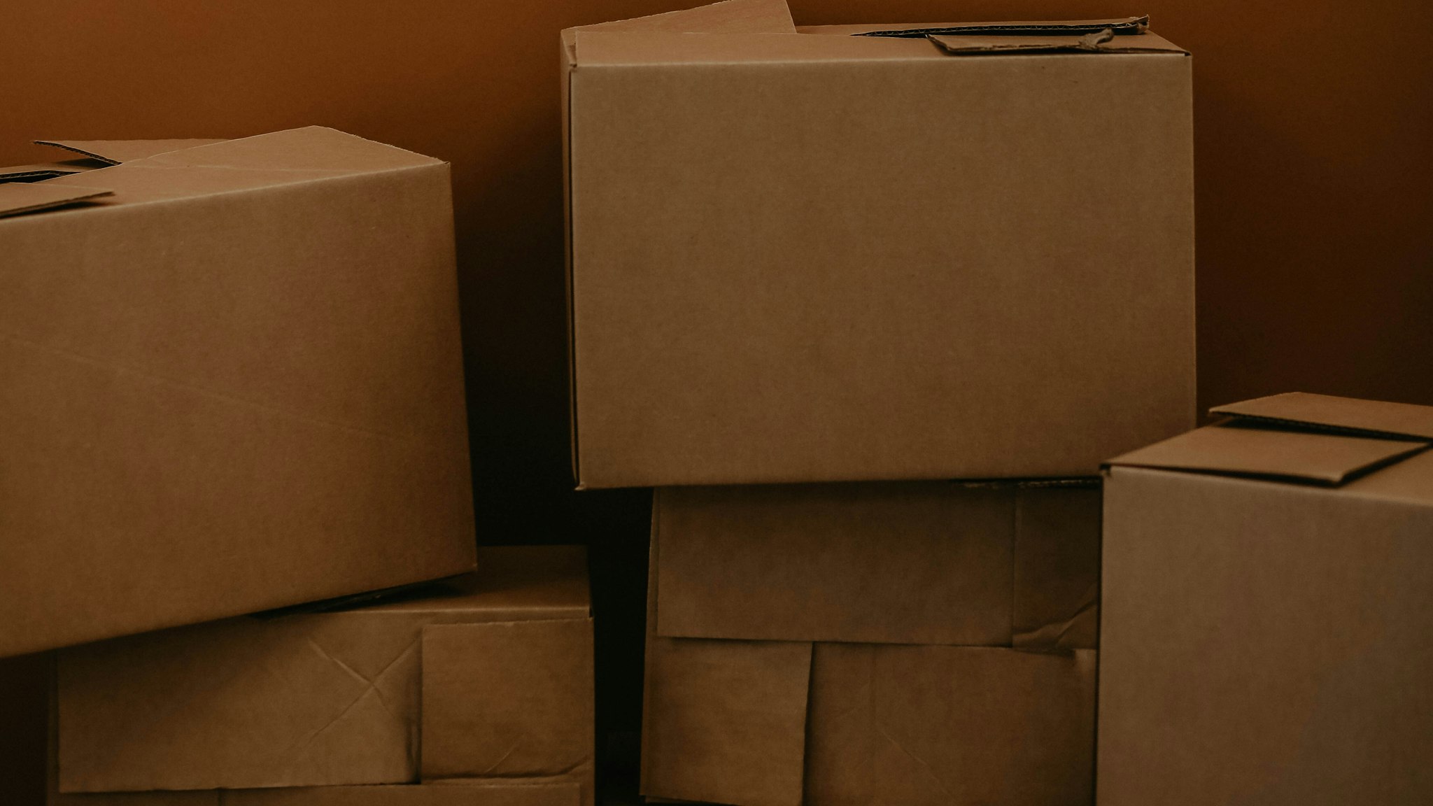 A stack of plain brown cardboard boxes against a brown background
