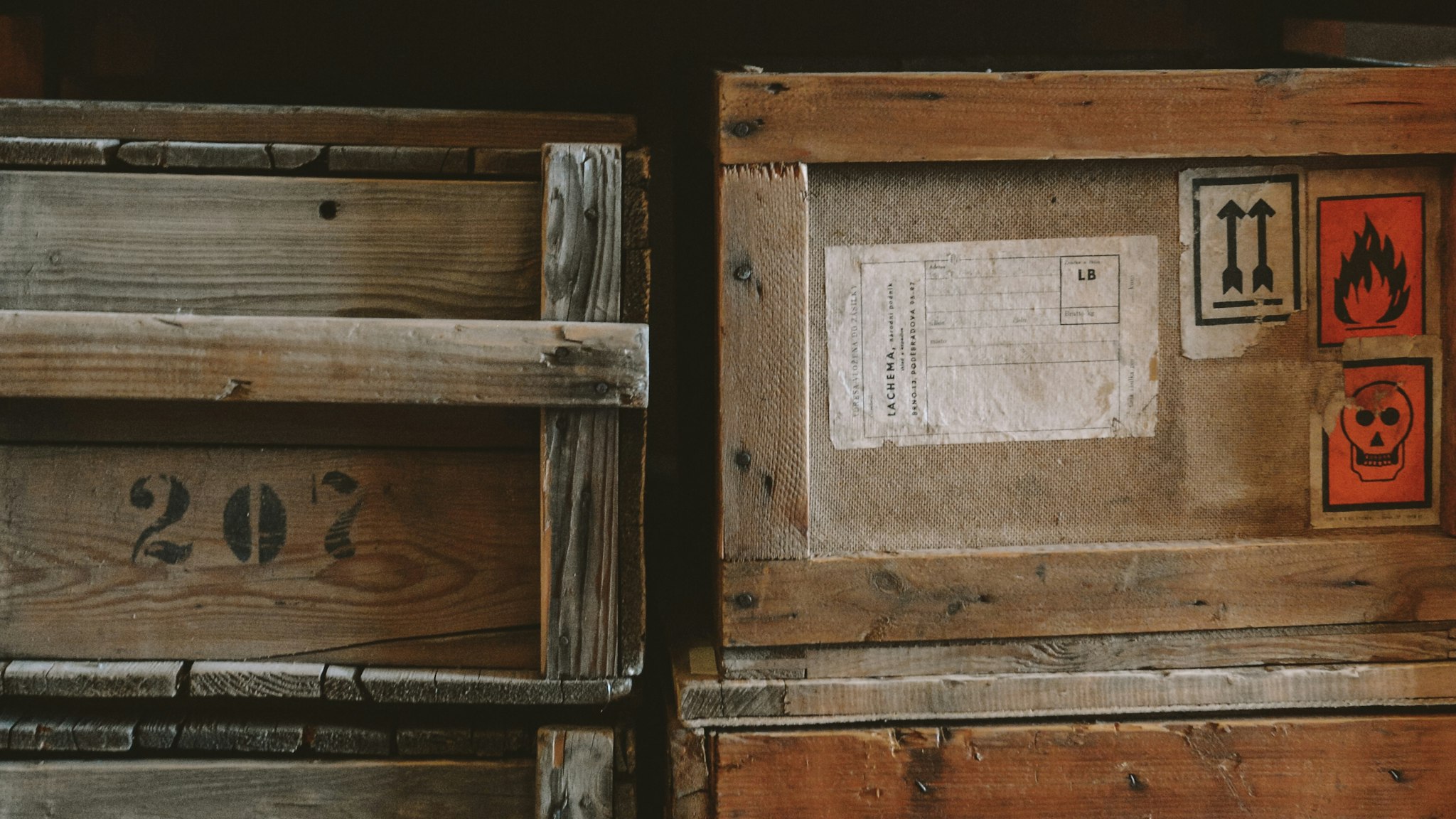 Rough wooden shipping crates stacked in rows inside a plain storage building.