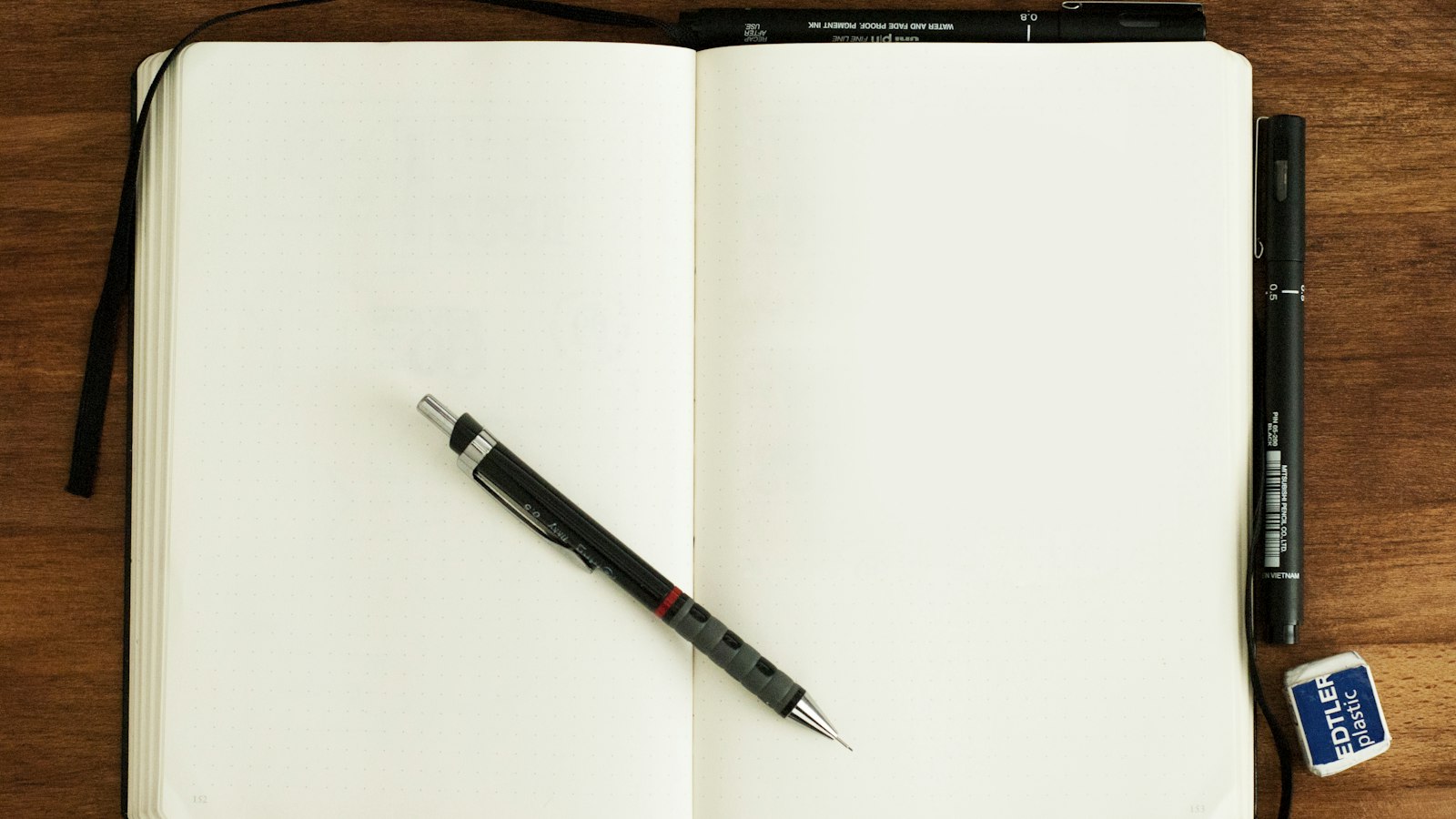 An open notebook and a pen: the frog is named in one written line the night before, so the morning starts with execution instead of a decision