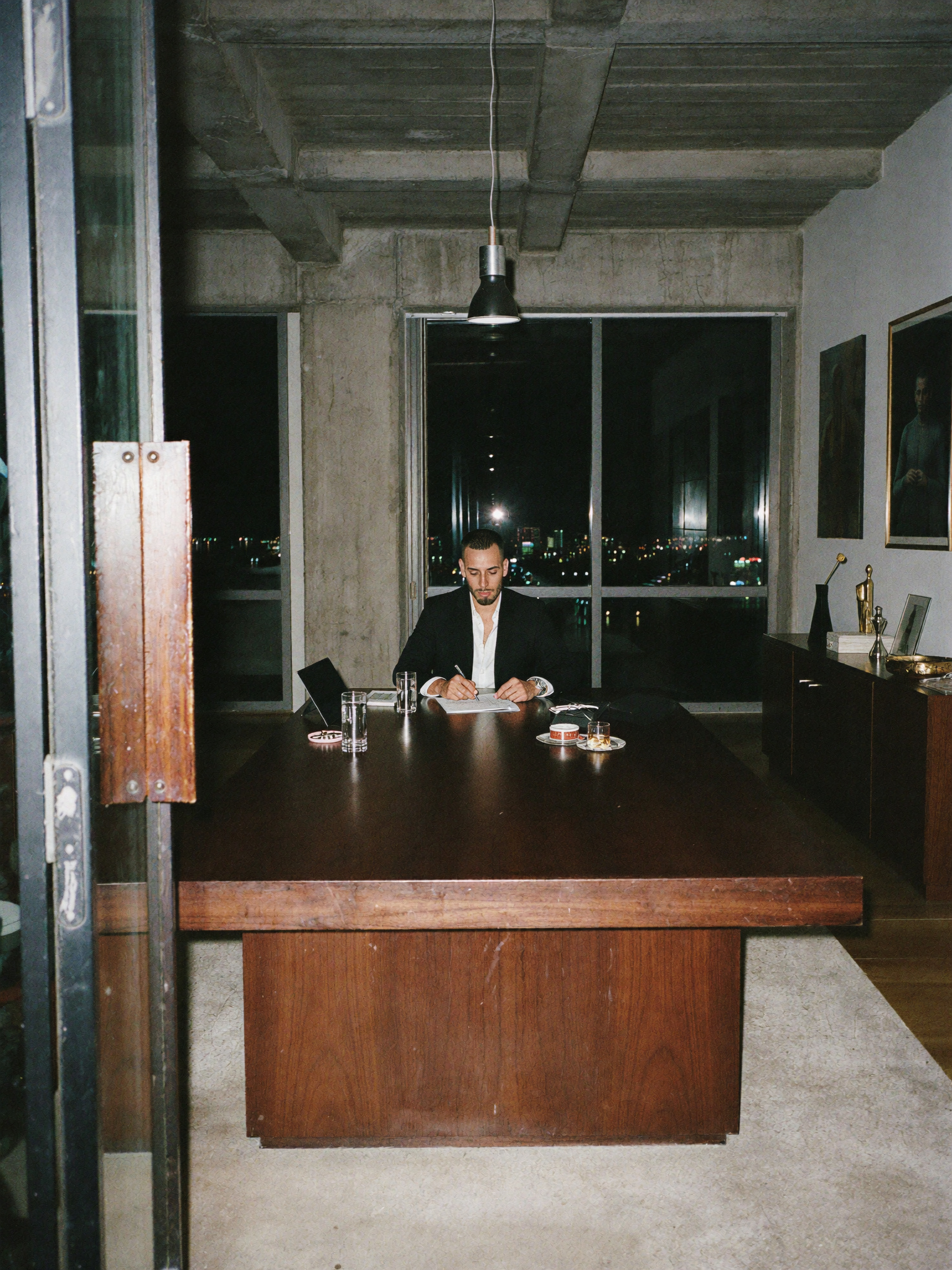 Cody Wise at a boardroom desk at night, city window behind him