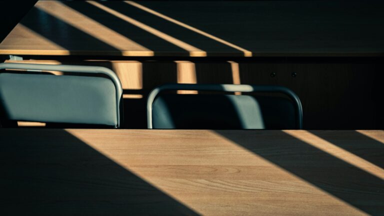 Empty wooden desks in early morning light: the hour before the inbox opens, when the hardest task should already be underway