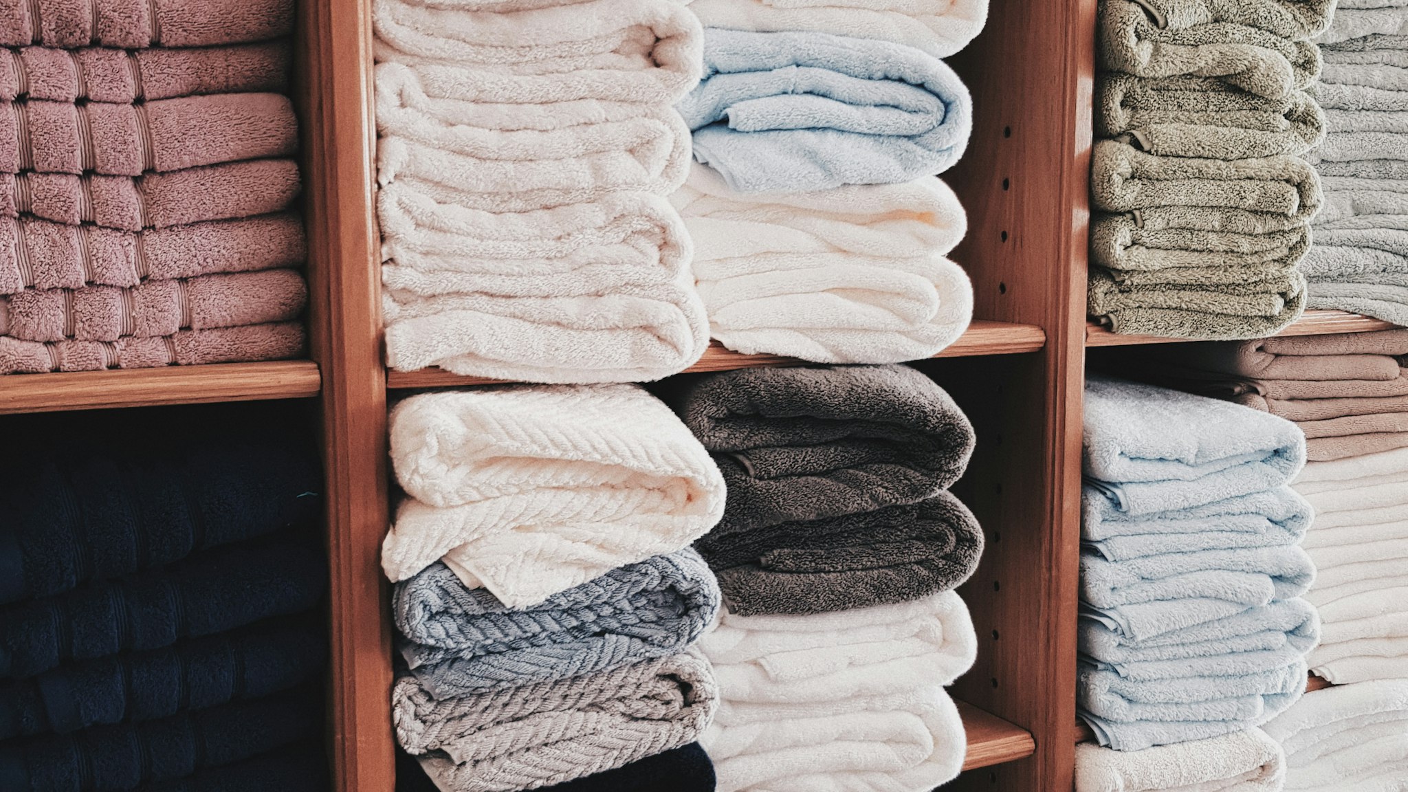 Folded white towels stacked on an open shelf