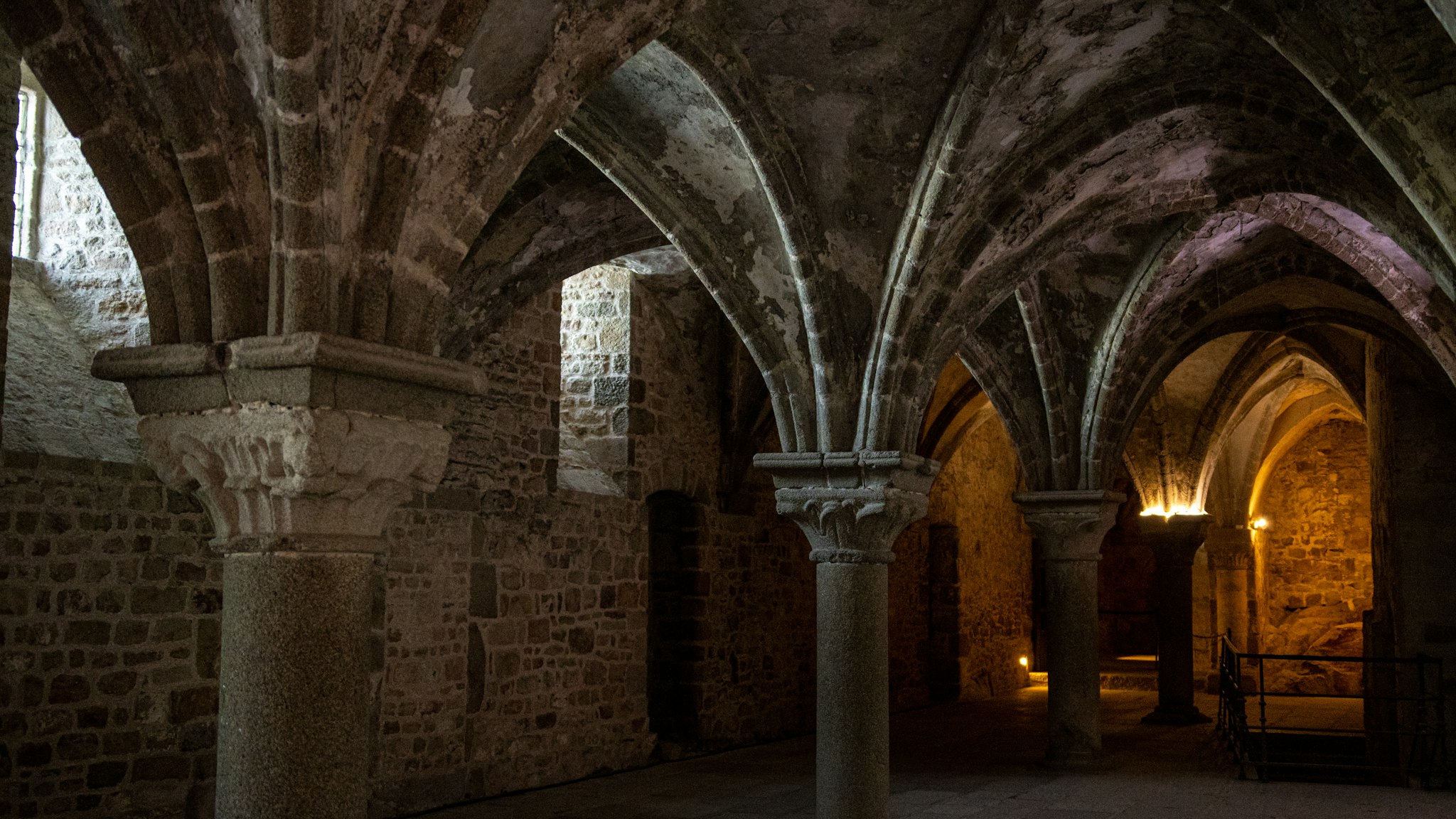A dimly lit medieval stone hall with arches and pillars