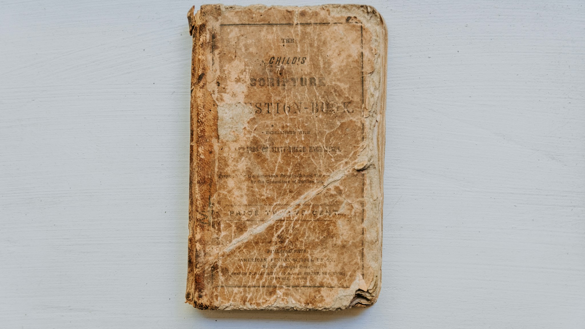 An old bound ledger book resting against a pale wall