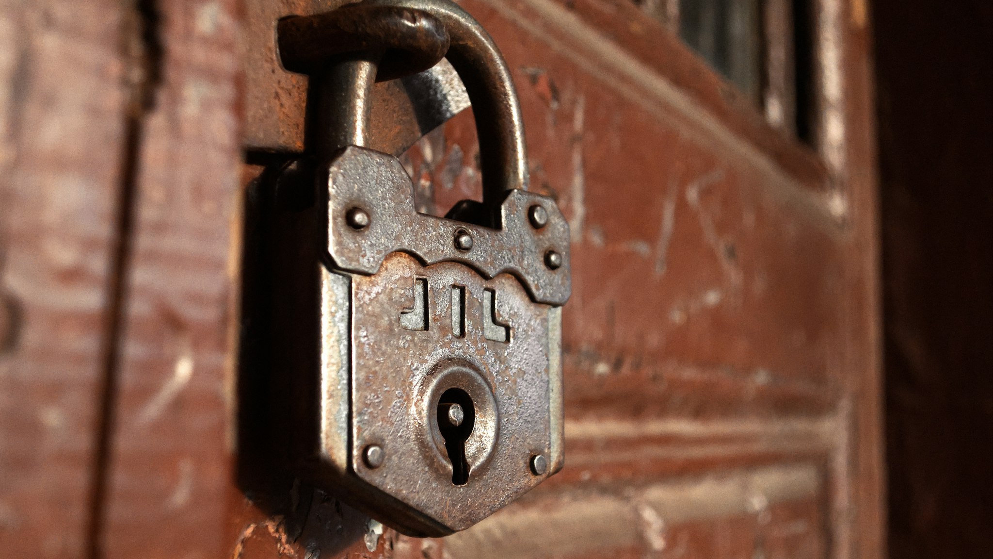 An old iron padlock fastened to a weathered wooden door