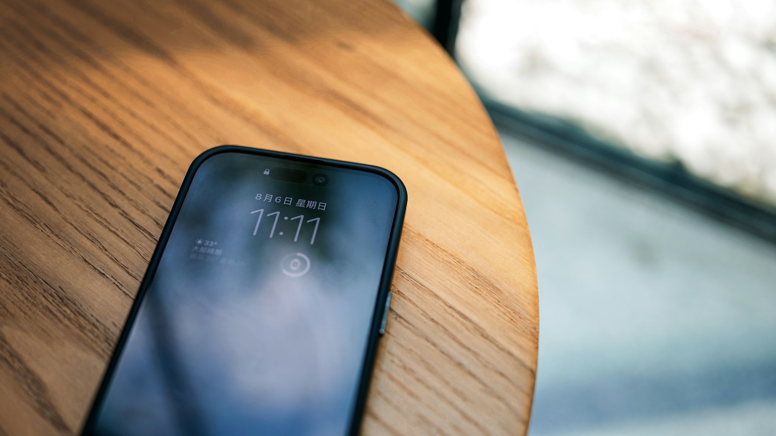 A phone left dark on a wooden table: the first block of the day belongs to the task you chose, not the one that arrived