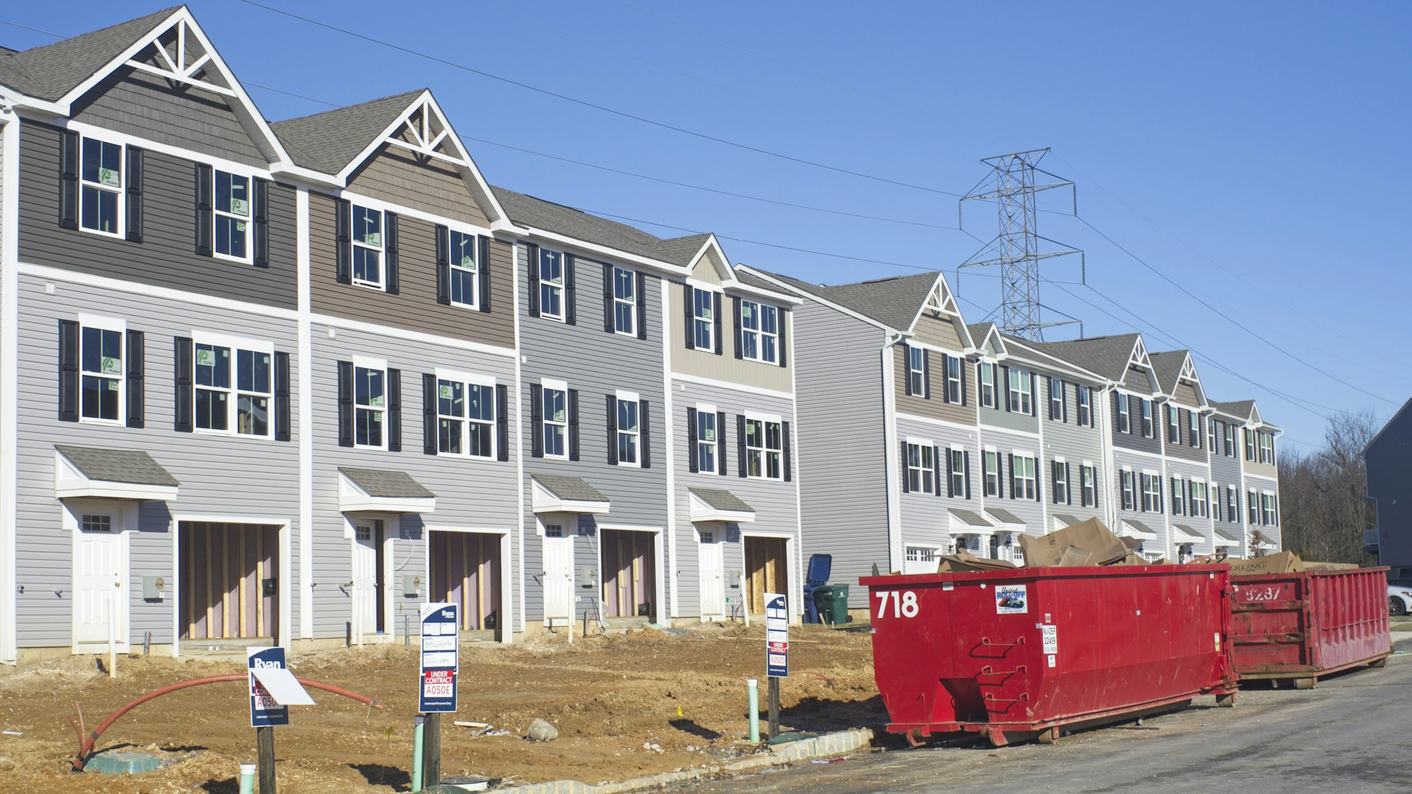 A row of finished new homes in a suburban development with a truck parked in front of them.
