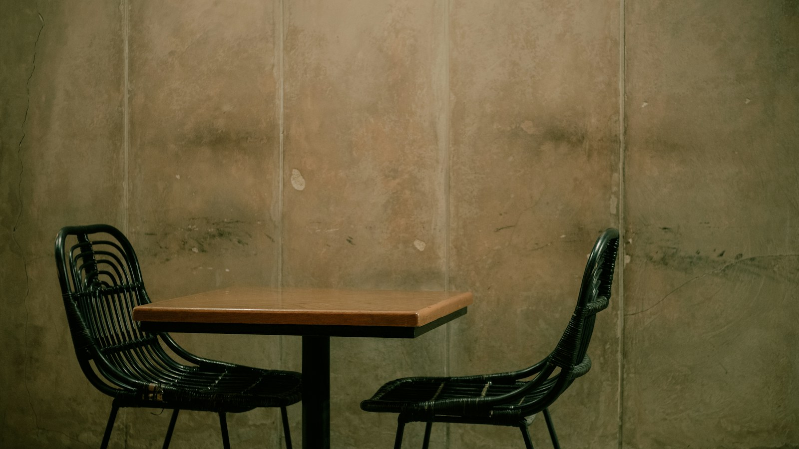 Two empty chairs at one small table, the second seat a founder has to decide to fill with someone who puts the business first